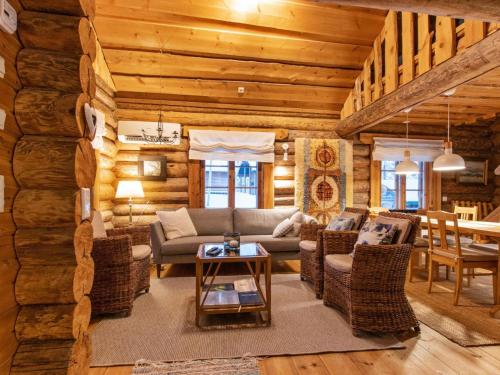 a living room with a couch and chairs in a log cabin at Holiday Home Tunturitorppa by Interhome in Äkäslompolo