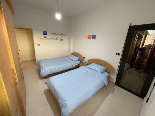 a room with two beds and a mirror at antelias mainroad apartment in An Naqqāsh