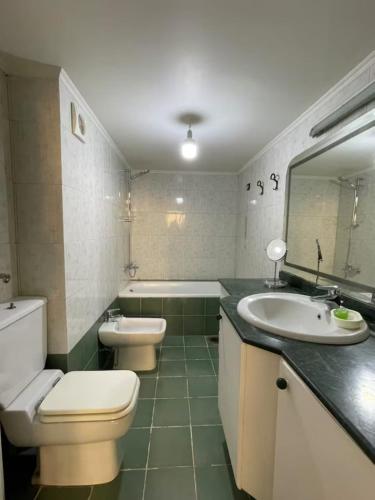 a bathroom with two toilets and a sink and a tub at antelias mainroad apartment in An Naqqāsh
