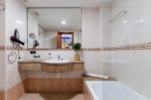 a bathroom with a sink and a tub and a mirror at Yourhouse Blau Blue 2 3 in Can Picafort