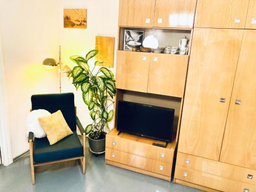 a living room with a tv and a chair and a cabinet at Apartment City Heart in Valmiera
