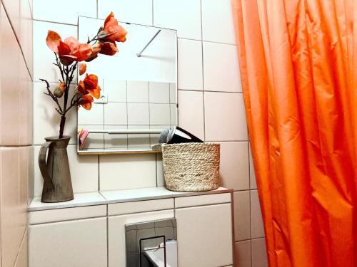 a bathroom with a mirror and a vase with flowers at Apartment City Heart in Valmiera