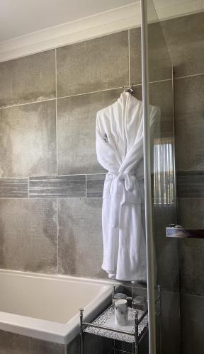 a bath tub with a robe hanging on a wall at The Anne Guest House in Maseru