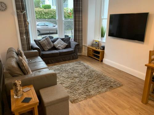 a living room with a couch and a flat screen tv at 2 Windsor House in Keswick