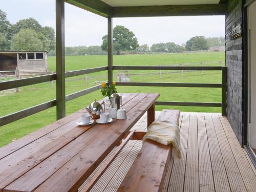 a wooden table on a porch with a view of a field at Ash Lodge in Bentley