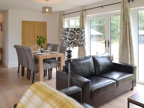 a living room with a leather couch and a table at Ash Lodge in Bentley