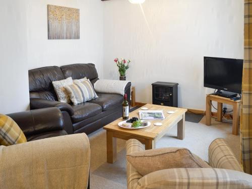 a living room with a leather couch and a coffee table at Clover Cottage in Keswick