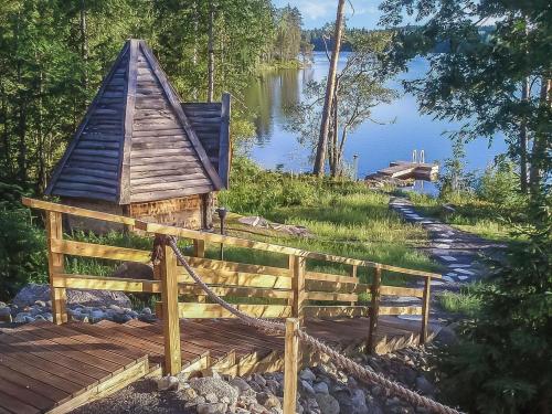 a wooden deck with a small house next to a lake at Holiday Home Paula by Interhome in Lihavanpää