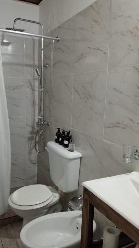 a white bathroom with a toilet and a sink at Bom Descanso in Realicó
