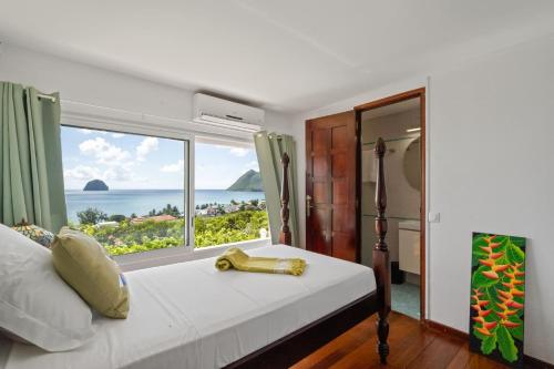 a bedroom with a bed with a view of the ocean at Villa Lueurs du Rocher in Le Diamant