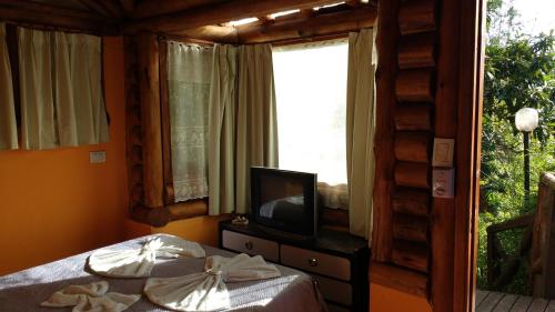 a bedroom with a bed and a tv and a window at Cabañas Manamar in Villa Gesell