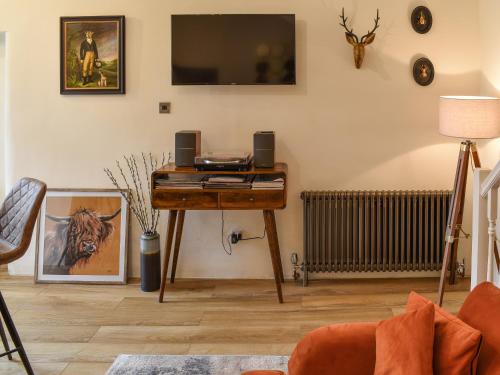 a living room with a desk with a tv on the wall at Methera Cottage in Ambleside