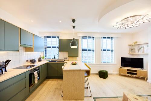 a kitchen with green cabinets and a flat screen tv at Aura - Elegant Retreat in Prime Leeds Location! in Headingley