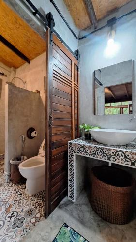 a bathroom with a sink and a toilet and a mirror at BaanRaiChayKhaoFarmStay in Nakhon Si Thammarat