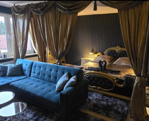 a living room with a blue couch in front of a bed at Gästezimmer vom Restaurant Saustall in Mestlin