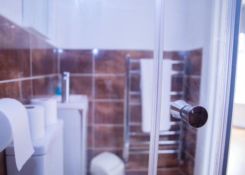 a bathroom with a glass shower door with a toilet at CONTRACTOR READY - spacious and bright 5 bed house! in Luton