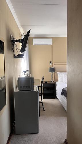 a bedroom with a bed and a desk with a tv at The Anne Guest House in Maseru