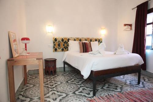 una camera da letto con un grande letto bianco e un tavolo di Riad Imndi a Marrakech