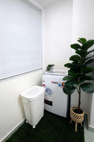 a bathroom with a plant next to a refrigerator at Homestay Tysha in Kampong Pulau Sebang