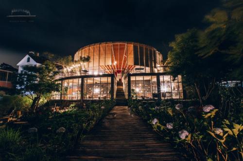 a large glass building with lights in it at night at The LOOP Boutique Hotel & Café in Da Lat
