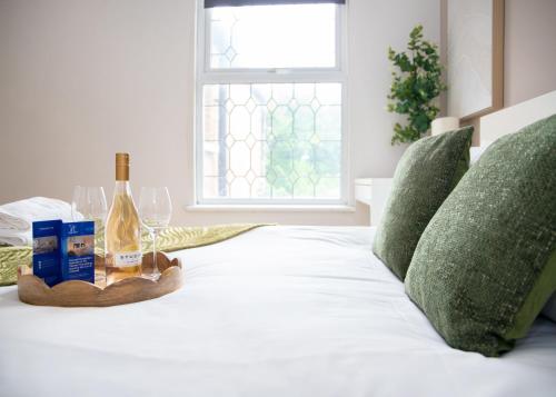 a bed with a bottle of wine and a tray with wine glasses at CONTRACTOR READY - spacious and bright 5 bed house! in Luton