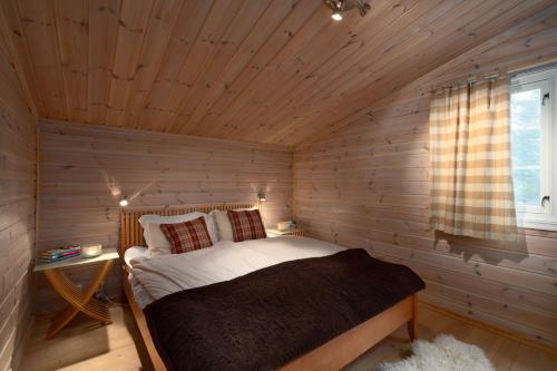 a bedroom with a bed in a wooden room at Geilolia Hyttetun in Geilo