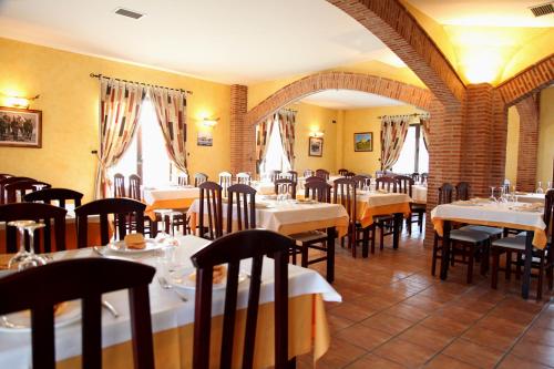un restaurante con mesas y sillas blancas y ventanas en Hotel Rural Venta Del Alon, en Villalón de Campos