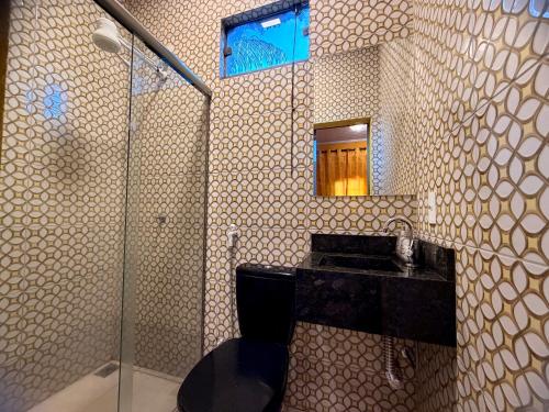 a bathroom with a shower and a toilet and a mirror at Pousada Complexo Girassol in Dourados