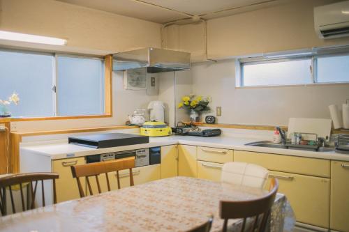 a kitchen with yellow cabinets and a table with chairs at 網代温泉源泉かけ流し 阿治古の宿 in Atami