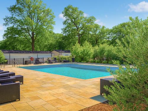 a swimming pool in a yard with chairs and trees at Highview in North Walsham