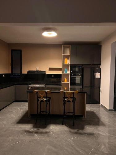 a large kitchen with two bar stools and a counter at HJ Appartements Haut Standing in Nouakchott