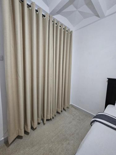 a bedroom with beige curtains on the wall at Upscale homes in Ongata Rongai 