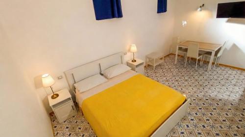 a bedroom with a yellow bed and a table at Villa Mary - Apartment in Trani