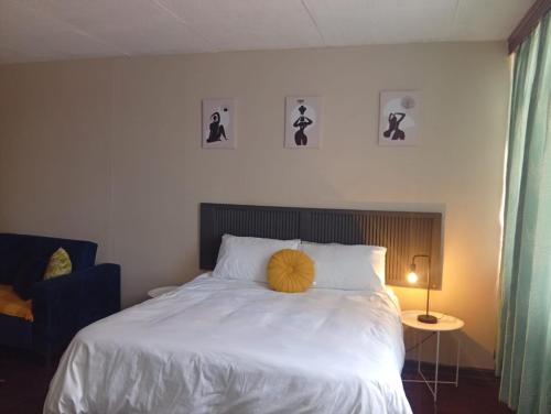 a bedroom with a bed with a yellow pillow on it at Comfy spacious apartment in Pretoria
