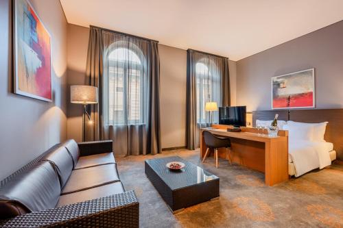 a hotel room with a couch and a desk and a bed at Hotel Museum Budapest in Budapest