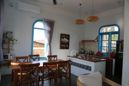 a kitchen with a wooden table and chairs and a kitchen with two windows at MayHome Binh Dinh in An Hòa