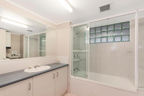 a bathroom with a sink and a glass shower at Surfcomber on the Beach in Maroochydore