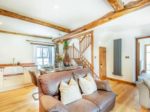 a living room with a leather couch and a kitchen at Inglenook Cottage in Ingleton
