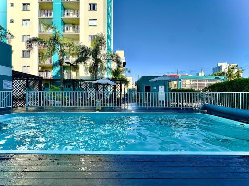 a large swimming pool in front of a building at Apto em Barra Velha 340m da PRAIA com SACADA com CHURRASQUEIRA, AR CONDICIONADO WI-FI, PISCINA, PORTARIA 24h, ACADEMIA MINI MERCADO e vaga de GARAGEM in Barra Velha
