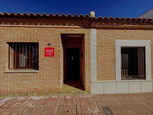 a brick building with a door and a sign on it at Casa Sol del Prado, Cerca De Puy Du Fou in Guadamur