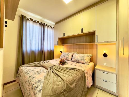 a bedroom with a bed and a large window at Apto em Barra Velha 340m da PRAIA com SACADA com CHURRASQUEIRA, AR CONDICIONADO WI-FI, PISCINA, PORTARIA 24h, ACADEMIA MINI MERCADO e vaga de GARAGEM in Barra Velha