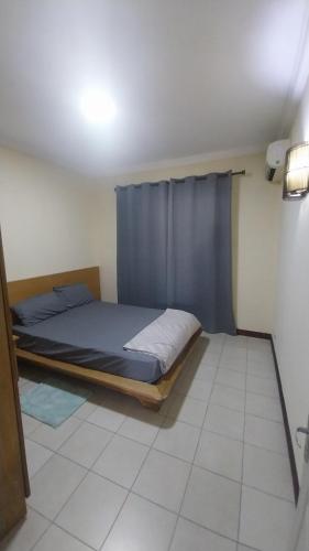a bedroom with a bed with a blue curtain at Residence Les Peupliers 05-06 in Flic-en-Flac
