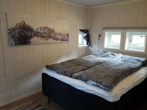 a bedroom with a bed and two windows at Moderne feriehus in Laupstad
