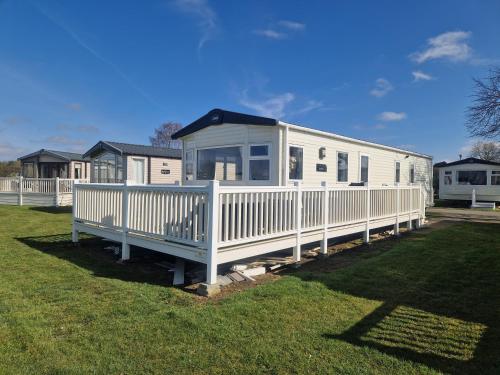 a large white mobile home with a porch at AMC Flamingo Land Caravan, Motorhome & Campervan Hire in Kirby Misperton
