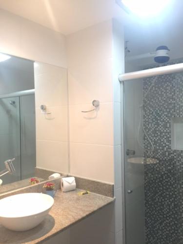 a bathroom with a sink and a glass shower at Apartamento temporada Farol Barra Flat in Salvador