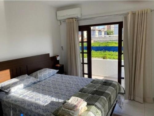a bedroom with a bed and a large window at RCM Vilas - Casa confortável 1 in Joinville