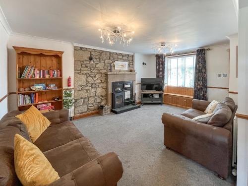 a living room with a couch and a fireplace at Swinton Mill Farm Cottage in Duns