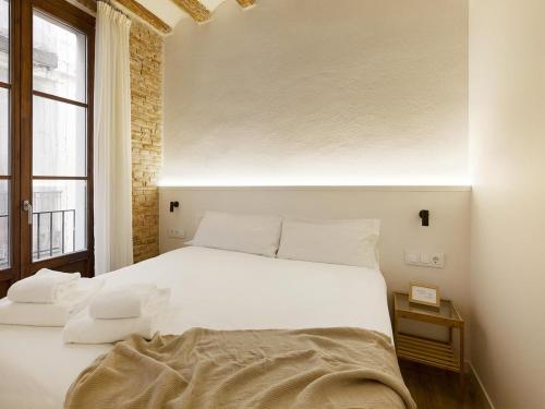 a white bed in a room with a window at Decô Apartments Barcelona-Born Apt. in Barcelona