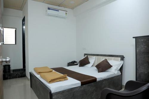 a bedroom with a bed with brown pillows and a chair at Hotel Sky Blue in Surat