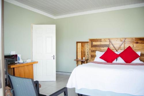 a bedroom with a white bed with red pillows at Bernliz Guest House in Bokong